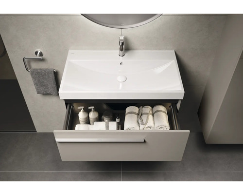 Waschtisch mit Schublade, Waschbecken, Handtüchern und Badartikeln in einem Badezimmer