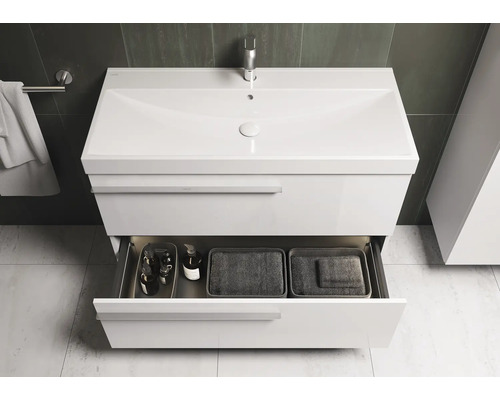 Weisser Waschtisch mit offenem Schubfach, das Badutensilien und Körbe enthält