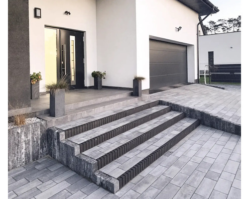 Extérieur d'une maison moderne avec une allée pavée et un escalier menant à l'entrée