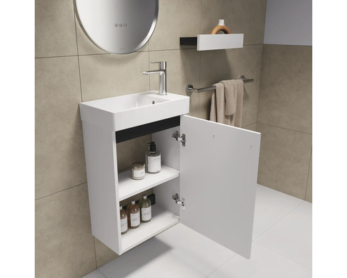 Salle de bains avec meuble sous-lavabo, lavabo et porte d'armoire ouverte