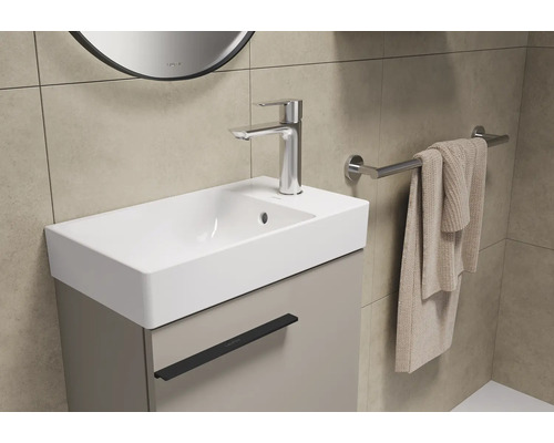 Lavabo de salle de bain avec meuble sous-lavabo, robinet et porte-serviettes.