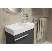 Salle de bains avec lavabo, robinet, serviette et miroir pour une ambiance lumineuse et organisée.