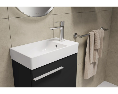 Lavabo avec robinet, porte-serviettes et miroir dans une salle de bain