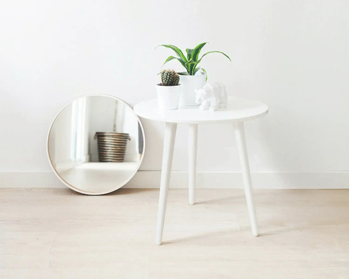 Dekorative Szene mit rundem Spiegel, Beistelltisch, Zimmerpflanzen und Skulptur