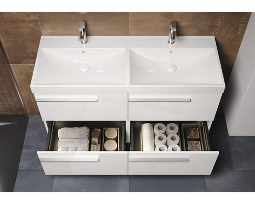 Meuble sous-lavabo blanc avec double vasque et tiroirs ouverts pour ranger les serviettes et le papier toilette.