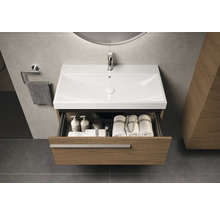 Meuble-lavabo avec tiroir ouvert, contenant des serviettes et des produits de soins, dans une salle de bain moderne
