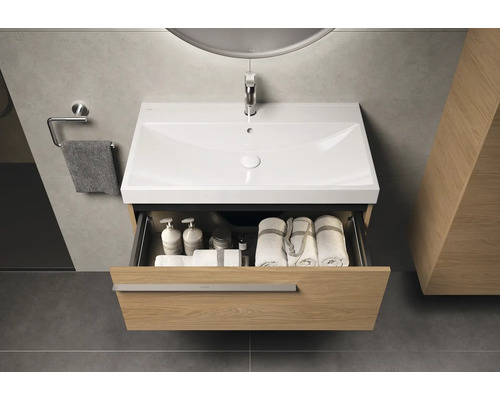 Meuble-lavabo avec tiroir ouvert, serviettes et articles de toilette à l'intérieur