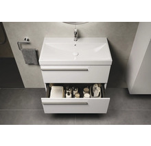 Meuble-lavabo avec tiroir ouvert, rempli de serviettes et d'accessoires de salle de bain, dans la salle de bain