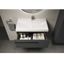 Meuble sous-lavabo avec tiroir ouvert, lavabo, serviettes et produits de soins dans la salle de bain