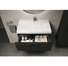 Meuble-lavabo avec tiroir ouvert, rempli de serviettes et de produits de soins dans la salle de bain.