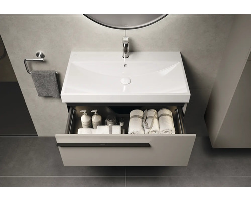 Meuble-lavabo de salle de bain avec tiroir, lavabo, serviette et robinetterie sous un miroir avec éclairage