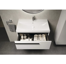 Meuble-lavabo avec tiroir ouvert, serviettes et produits de soins dans la salle de bains.