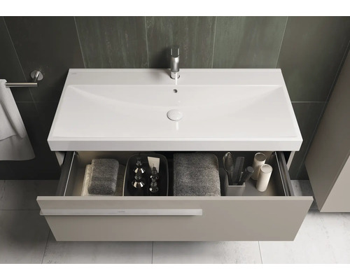 Salle de bains avec meuble sous-vasque, lavabo, robinetterie et tiroir ouvert avec serviettes et accessoires de bain