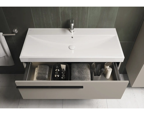 Meuble sous-lavabo avec tiroir ouvert et divers accessoires de salle de bain