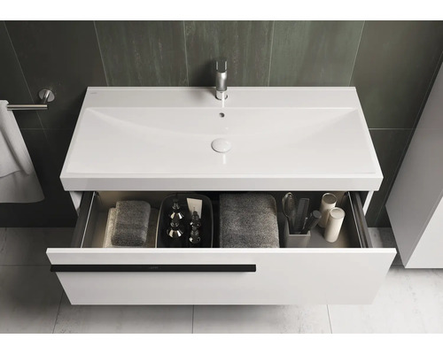 Meuble-lavabo avec tiroir ouvert, serviettes et articles de toilette dans la salle de bain