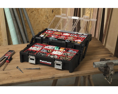 Geöffnete, schwarze Pattfield Sortimentsbox mit transparentem Deckel und diversen Schrauben, Nägeln und Dübeln auf einem Holztisch.