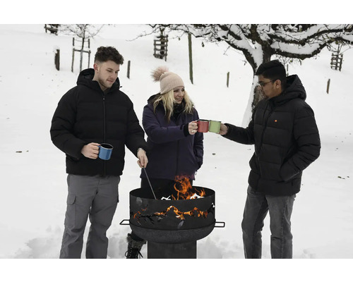Drei Personen stehen im Schnee um eine Feuerschale und halten Tassen
