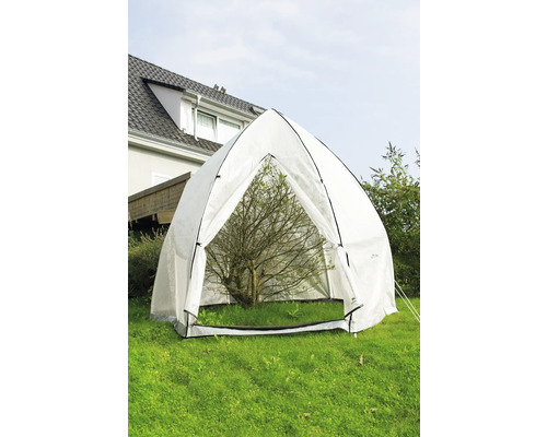 Scène de jardin avec une tente pour plantes transparente protégeant un petit arbre.