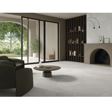 Heller Wohnraum mit Fliesenboden, Sessel, Couchtisch und Regal