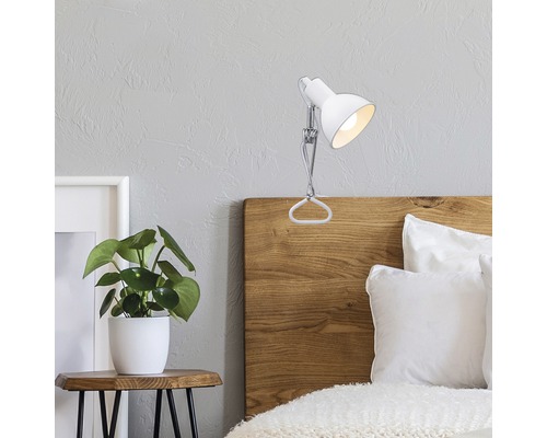 Lampe à pince sur lit avec table de chevet et plante