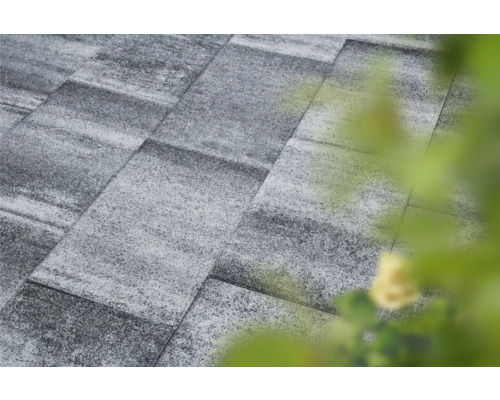 Graue Pflastersteine bilden eine Gartenfläche.