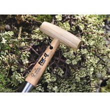 Gartenwerkzeug mit Holzgriff und for-q Logo, umgeben von Pflanzen