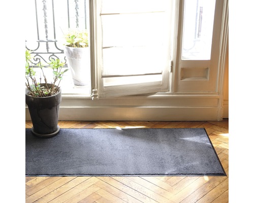 Graue Fussmatte vor einer Tür auf einem Holzboden