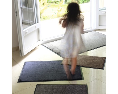Eingangsbereich mit Fussmatten in verschiedenen Farbtönen vor einer geöffneten Tür