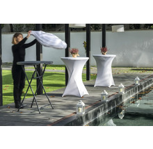 Szene mit Stehtischen, Tischhussen, Laternen und einer Person beim Auflegen eines Tuchs.