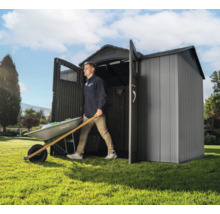 Un homme sort une brouette d'un abri de jardin