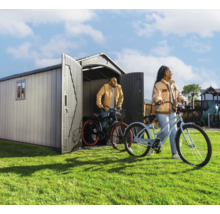 Scène de jardin avec abri de jardin et deux personnes avec des vélos sur la pelouse