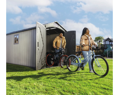 Scène de jardin avec abri de jardin et deux personnes avec des vélos sur la pelouse