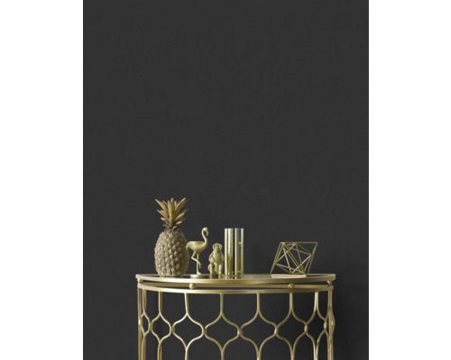 Ananas, flamant rose, singe, vase et figure géométrique décoratifs dorés sur une table d'appoint dorée devant un mur sombre.