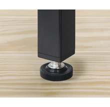 Vue détaillée d'un pied de table noir avec pied réglable sur un plancher en bois.