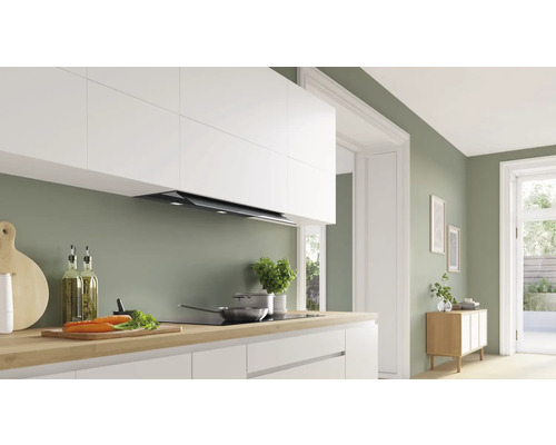 Küchenszene mit Dunstabzugshaube, Kochfeld und Küchenutensilien auf einer Arbeitsplatte.