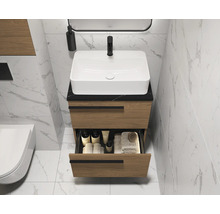Meuble-lavabo de salle de bains avec tiroirs, vasque à poser et robinet devant un mur carrelé
