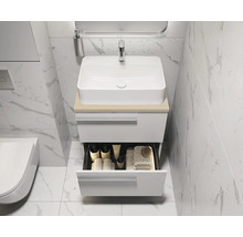 Meuble-lavabo avec tiroir ouvert contenant des accessoires de bain tels que des serviettes et des produits de soins