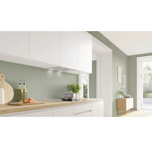 Helle Küche mit Dunstabzugshaube, Kochfeld und Küchenutensilien auf der Arbeitsfläche.