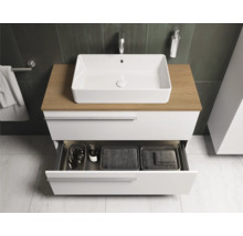 Salle de bain moderne avec meuble-lavabo blanc, plateau en bois et tiroir ouvert pour ranger les accessoires de salle de bain.