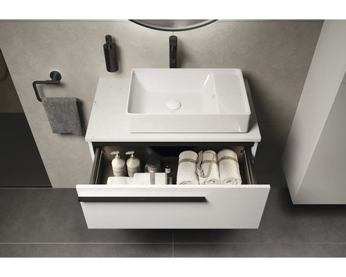 Salle de bains moderne avec meuble-lavabo, vasque à poser rectangulaire et tiroir ouvert avec serviettes et produits de soin.