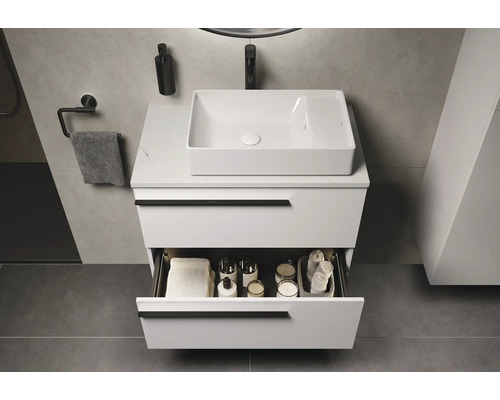 Salle de bains moderne avec meuble-lavabo blanc, lavabo et tiroir ouvert pour ranger les articles de toilette