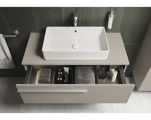 Vue de salle de bain avec lavabo et tiroir ouvert sous le plan de travail, dans lequel sont rangés les serviettes et les accessoires de bain.