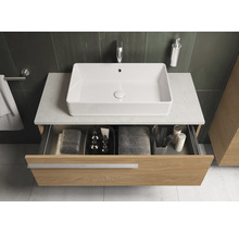 Meuble sous-lavabo avec tiroir ouvert, lavabo, serviettes et accessoires de salle de bain.