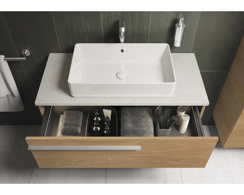 Meuble sous-lavabo avec tiroir ouvert, lavabo, serviettes et accessoires de salle de bain.