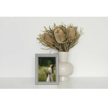 Dekoratives Stillleben mit Bilderrahmen, Vase und Trockenblumenarrangement