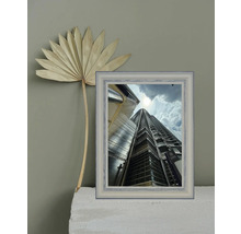 Dekorative Szene mit getrocknetem Palmenblatt und gerahmtem Foto eines Wolkenkratzers