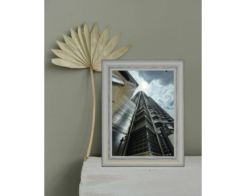 Dekorative Szene mit getrocknetem Palmenblatt und gerahmtem Foto eines Wolkenkratzers