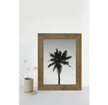 Une image encadrée d'un palmier se trouve à côté d'un vase avec des fleurs séchées.