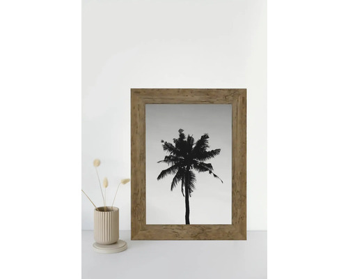 Une image encadrée d'un palmier se trouve à côté d'un vase avec des fleurs séchées.