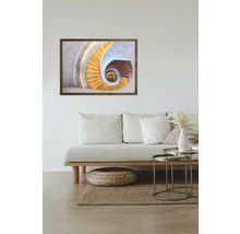 Une image encadrée d'un escalier en colimaçon est suspendue au-dessus d'un canapé dans un salon lumineux.